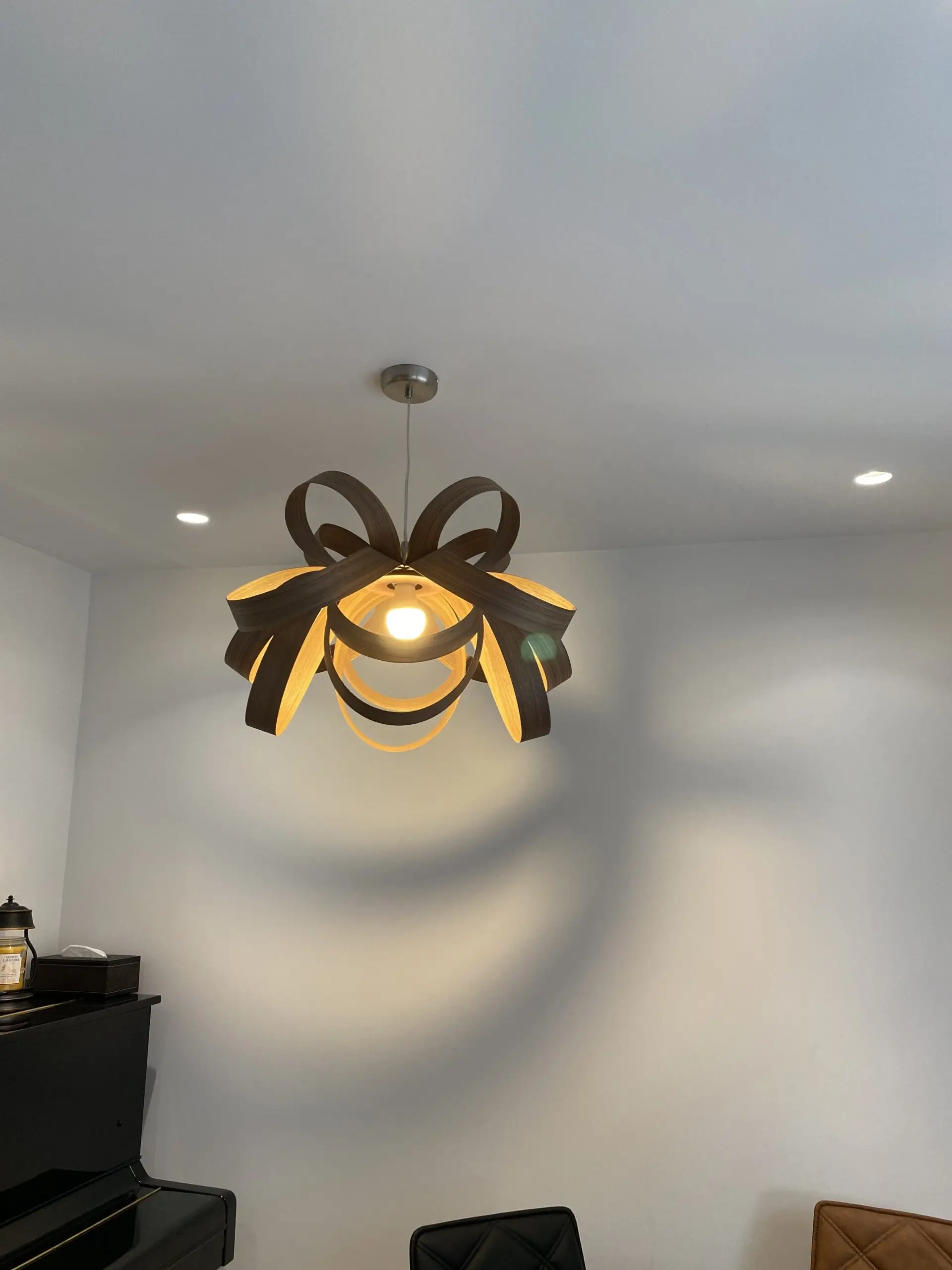 Modern pendant light with sculptural, ribbon-like metal design casting artistic shadows on a white ceiling, installed by Rajvar Technologies.